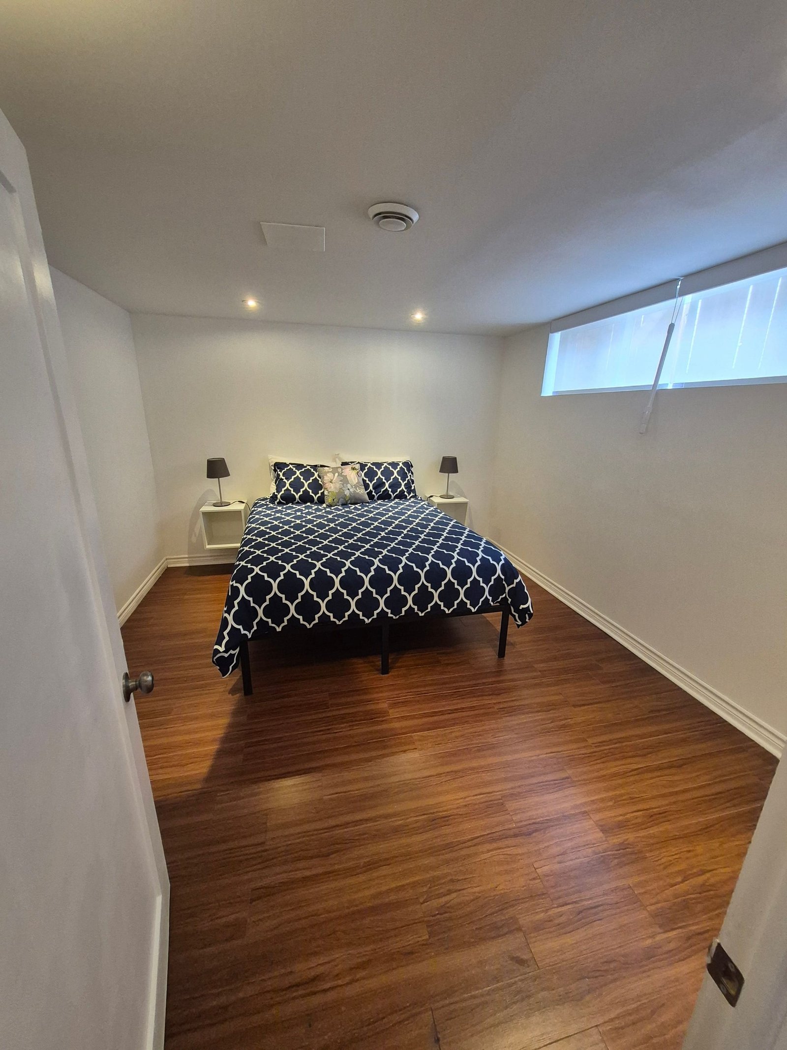 Bedroom 2 with a queen bed, bedside lamps, and a wide window